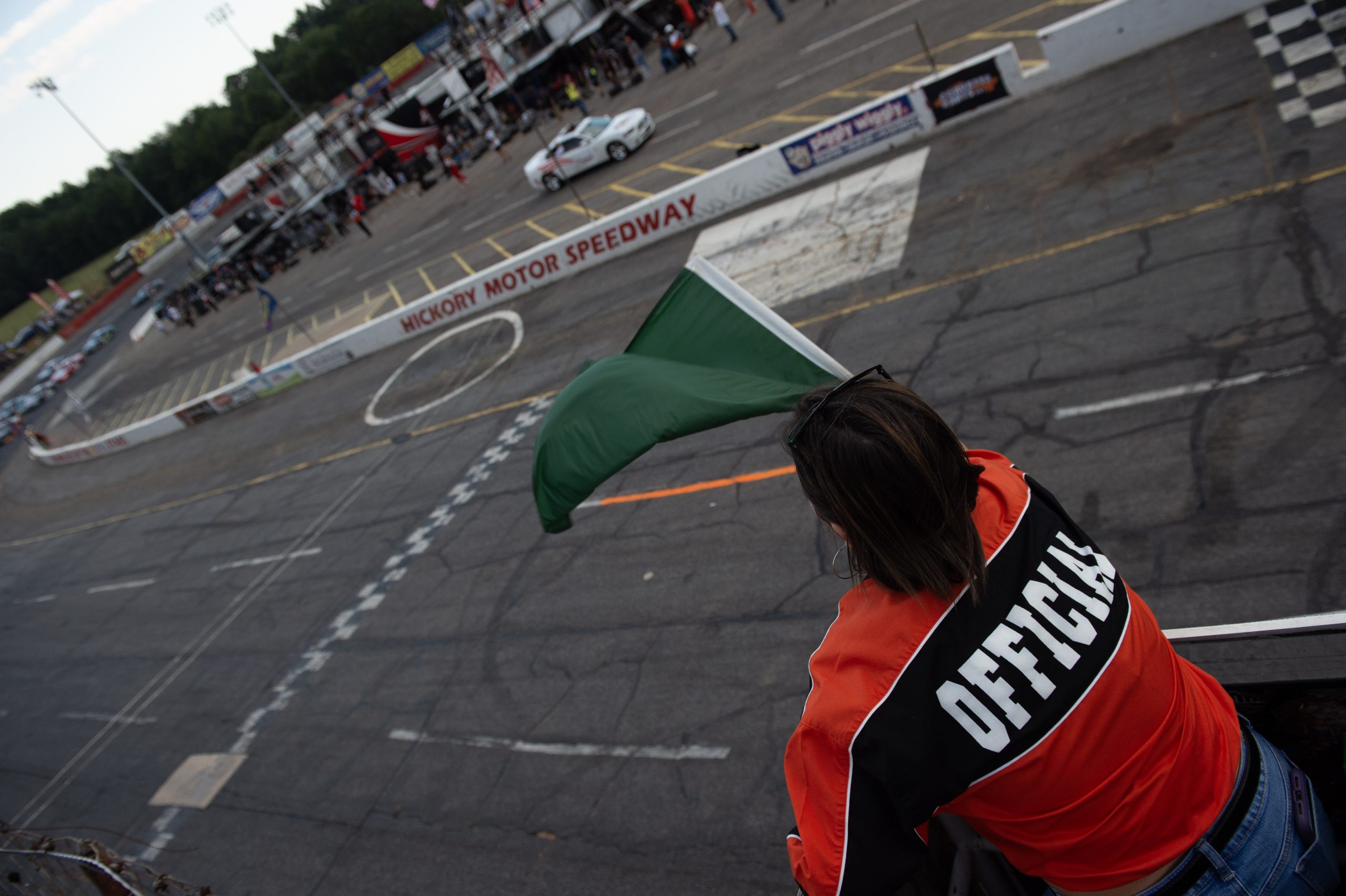 118-_JH36068 Woman wearing a red shirt, waving a checkered flag over the racing surface.